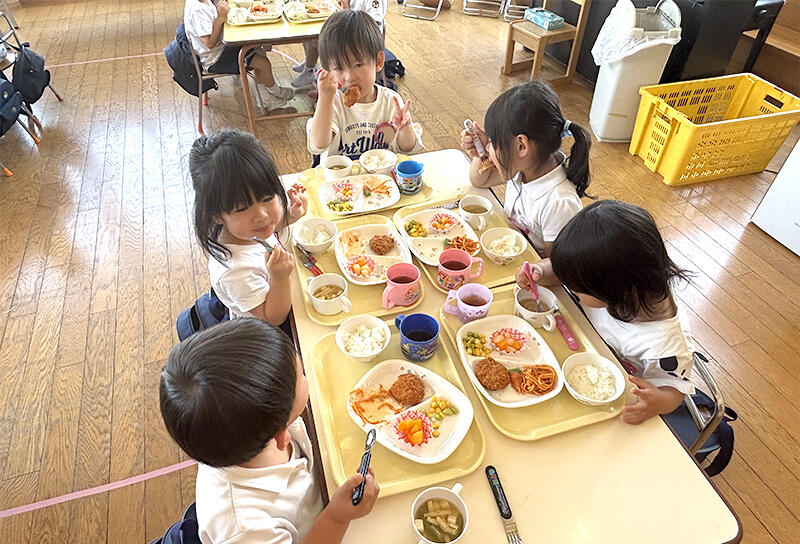 美味しそうに給食を食べている5人の園児の写真