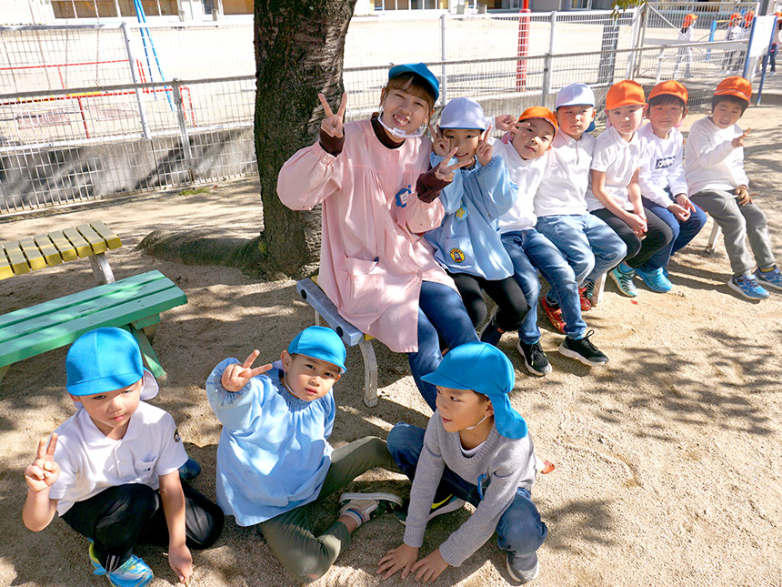 写真：福島ルンビニー幼稚園：園児と並んで笑顔の先生