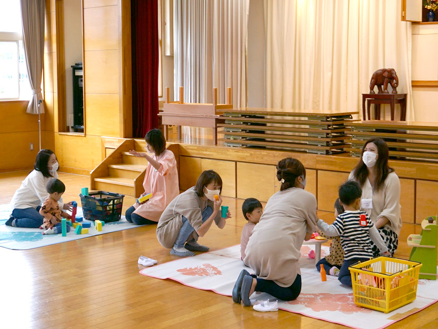 写真：福島ルンビニー幼稚園で保育体験をしている未就園児とお母さんと、先生。体育館でつみきなどで楽しそうに遊んでいる