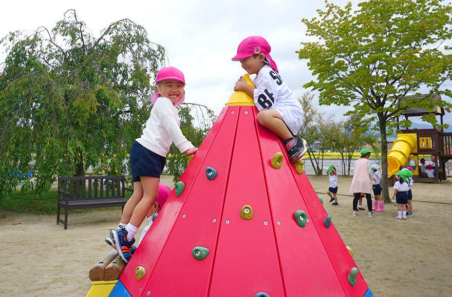 写真:園庭にある遊具で遊んでいる2人の園児